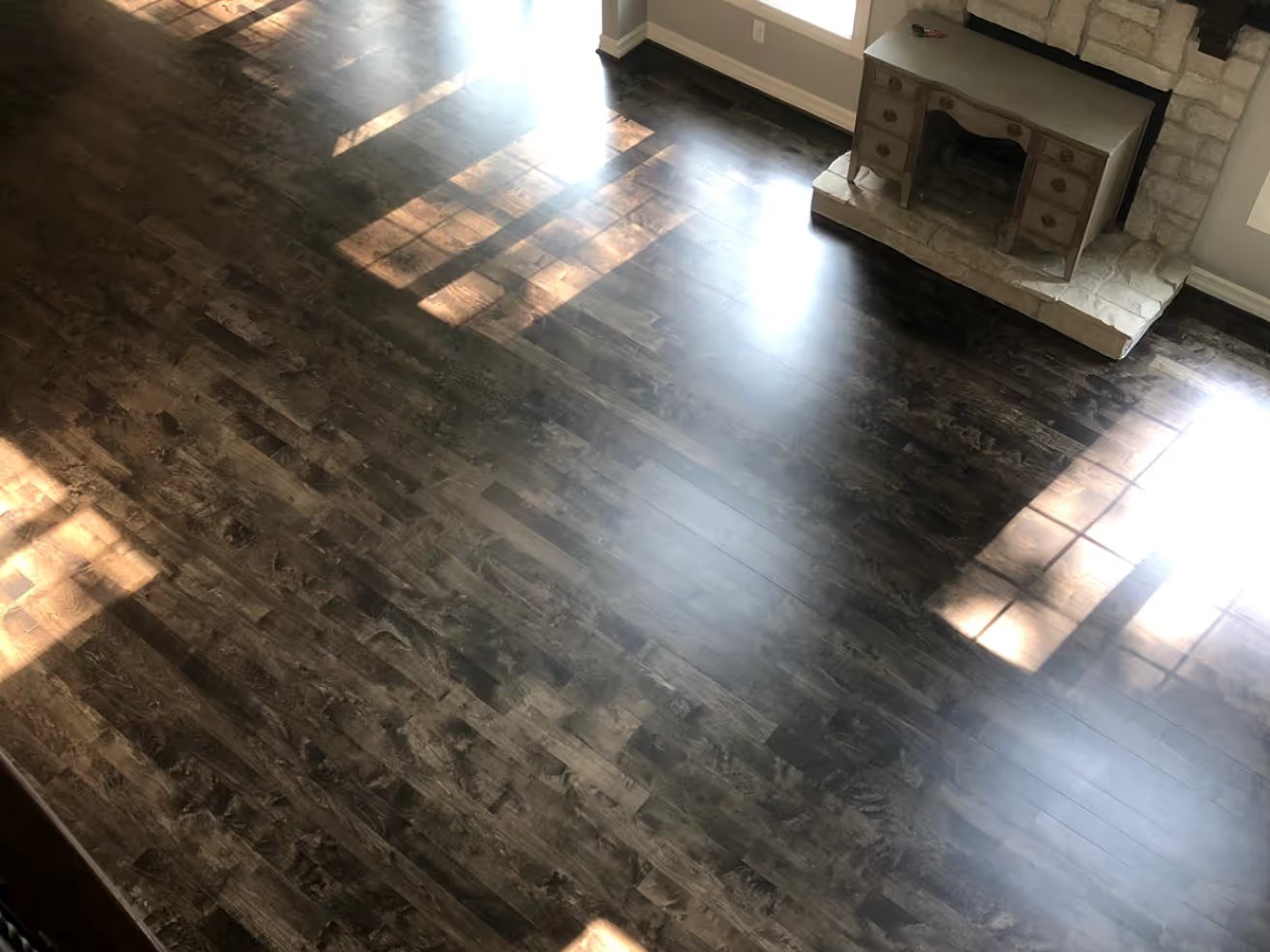 Dark-stained refinished floor with a high-gloss sheen catching the window light