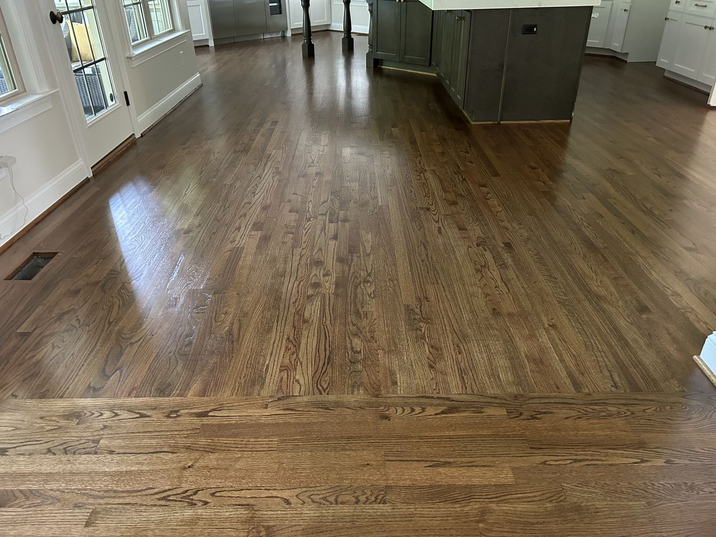 Dark-stained refinished hardwood through a kitchen