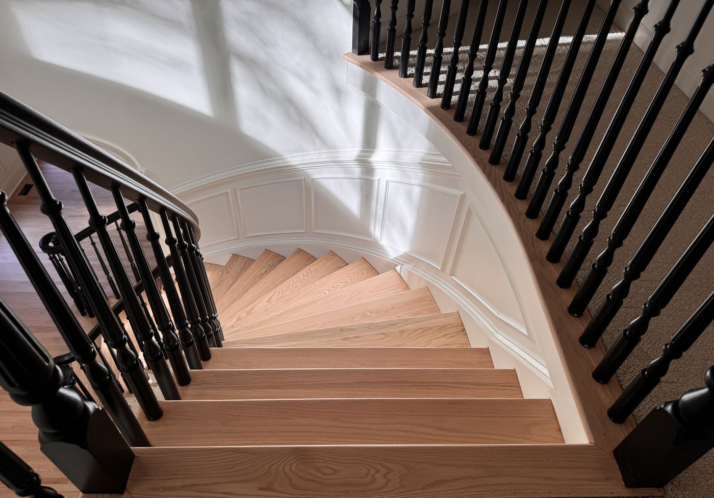 Curved staircase with light treads and black balusters