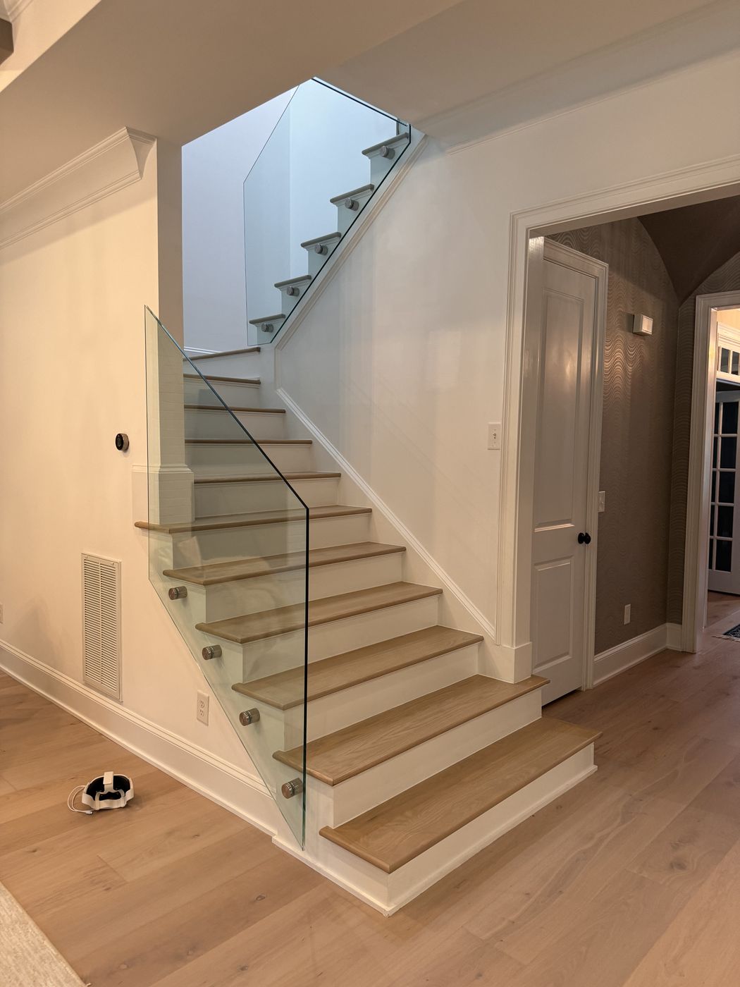 Staircase with light wood treads and a glass rail