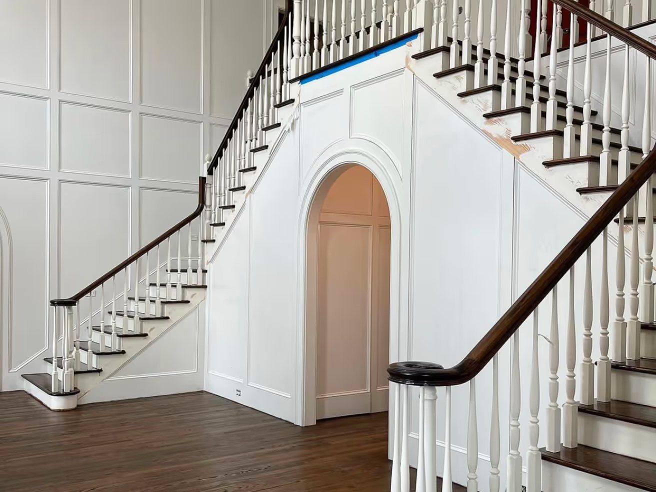 Grand staircase with dark treads and an arched under-stair detail