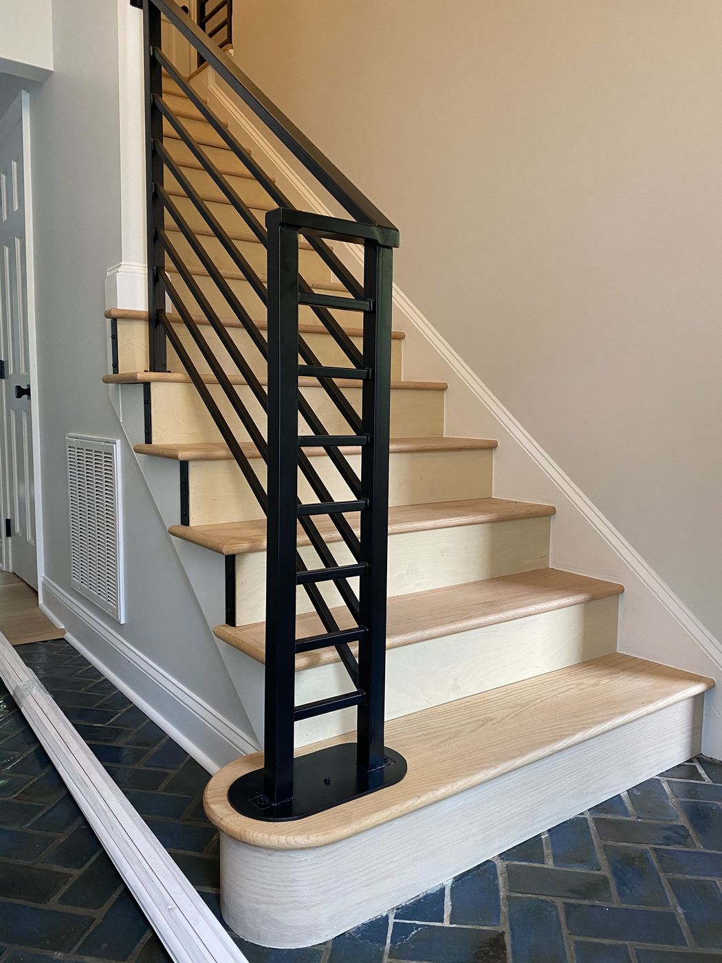 Staircase with light wood treads and a black steel rail