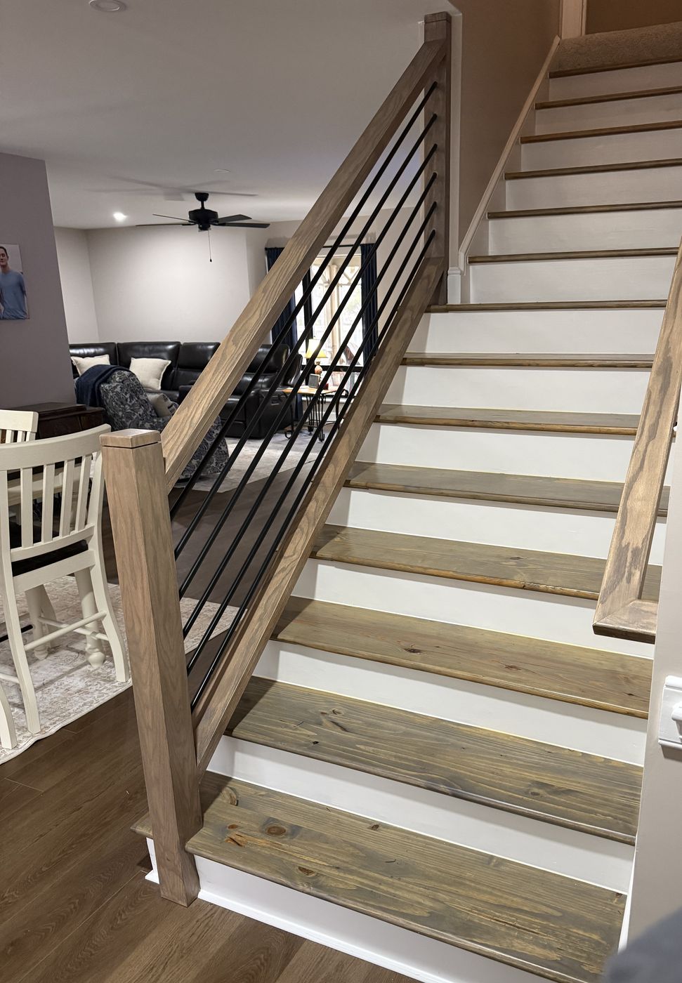 Staircase with wood treads, white risers, and a black iron rail